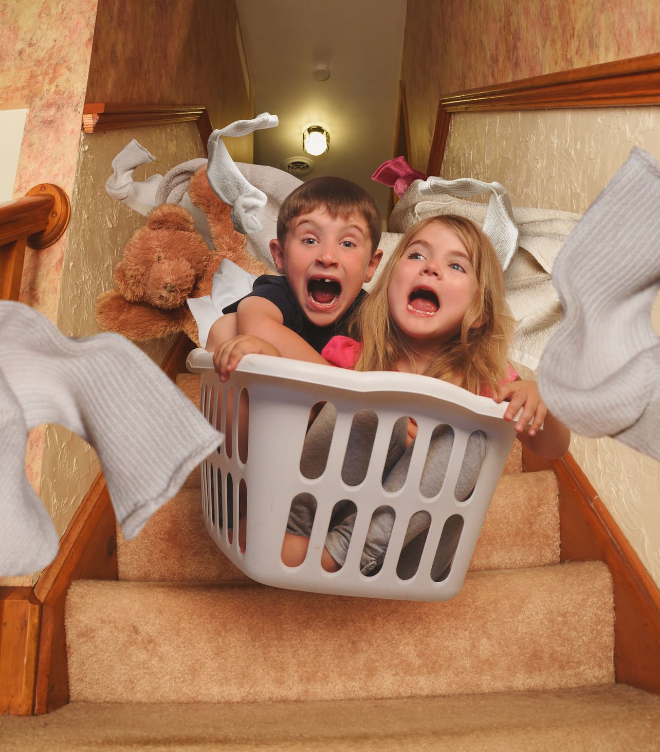 Kids playing with a washing basket on the stairs